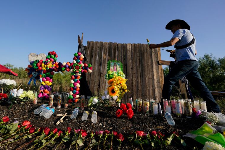 Roberto Marquez of Dallas adds a flower to a makeshift memorial at the site where officials found dozens of people dead in an abandoned tractor-trailer.