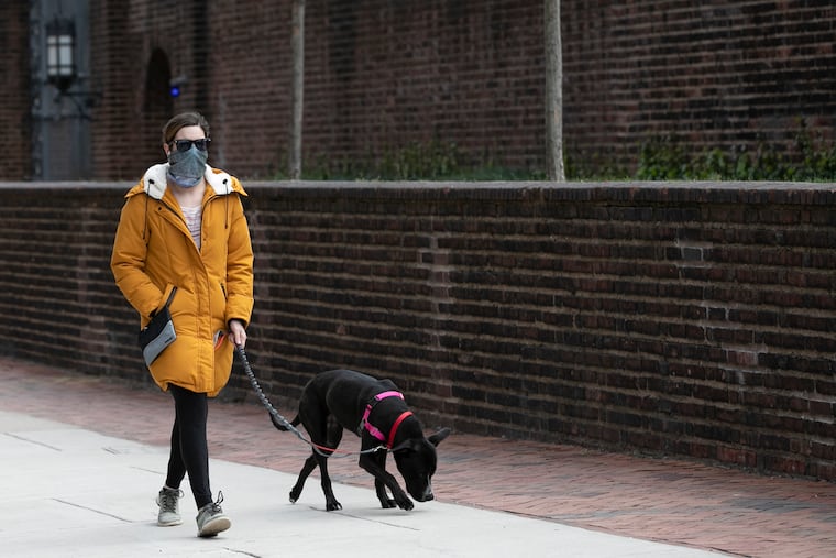 A pedestrian wears a protective face mask out in front of the Penn Museum in Philadelphia on Friday. Gov. Tom Wolf is now urging Pennsylvanians to wear masks in public due to the spread of the coronavirus.
