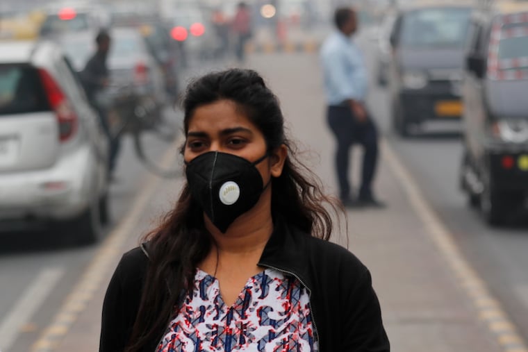 A commuter walks wearing a pollution mask amidst thick layer of smog in New Delhi, India, Thursday, Nov. 14, 2019. Schools in India's capital have been shut for Thursday and Friday after air quality plunged to a severe category for the third consecutive day, enveloping New Delhi in a thick gray haze of noxious air. (AP Photo/Manish Swarup)