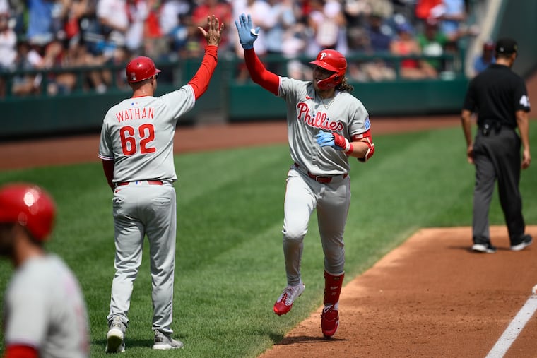 Philadelphia Phillies' Alec Bohm, right, celebrates his three-run home run with third base coach Dusty Wathan (62) as he rounds the bases during the second inning of a baseball game against the Washington Nationals, Sunday, Aug. 17, 2025, in Washington. (AP Photo/Nick Wass)