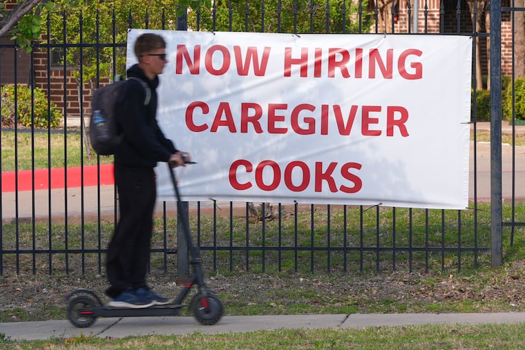 A now hiring sign sits by the sidewalk as a rider on a scooter passes in Garland, Texas, Monday, March 23, 2026. A new Gallup poll shows just 28% of workers said now is a "good time" to find a quality job.