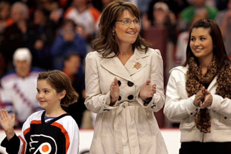 Sarah Palin, and daughters Piper (left) and Willow, wave to the crowd in the Wachovia Center as she walks on to the ice to drop the first puck of the Flyers' season. (Laurence Kesterson / Inquirer)