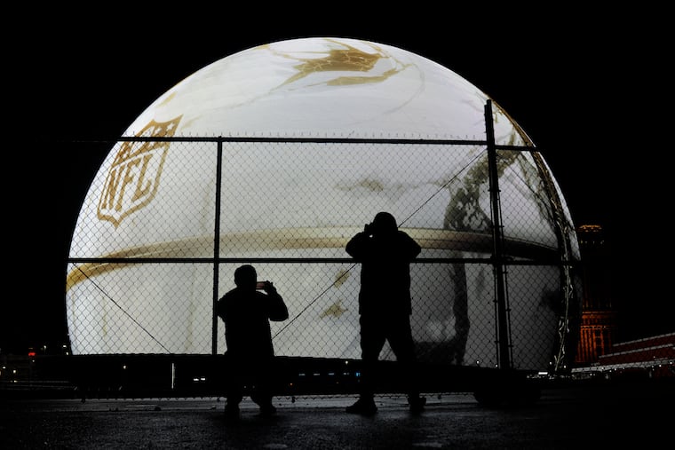 People take photos of the Sphere featuring an ad for the NFL ahead of Super Bowl 58 Sunday.