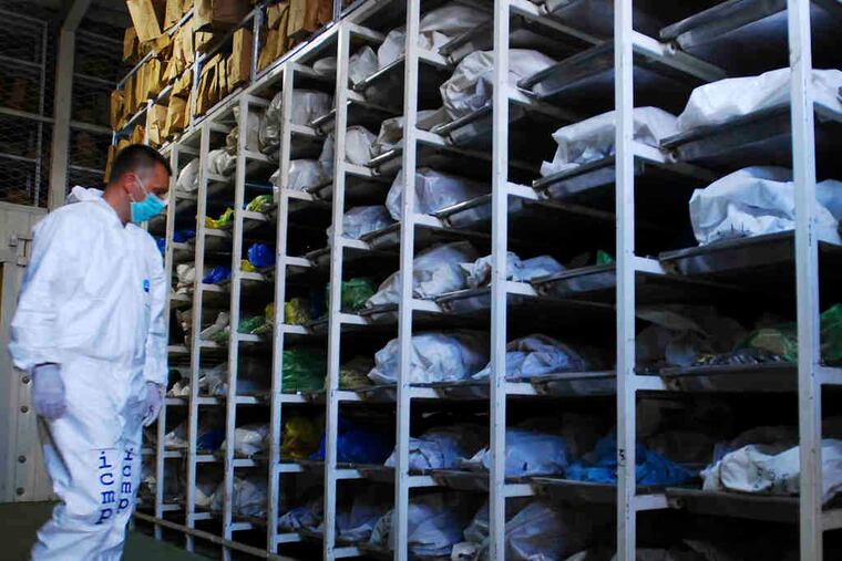 A Bosnian member of the International Commission on Missing Persons inspects remains of Bosnian war victims that were exhumed from mass graves for DNA identification.