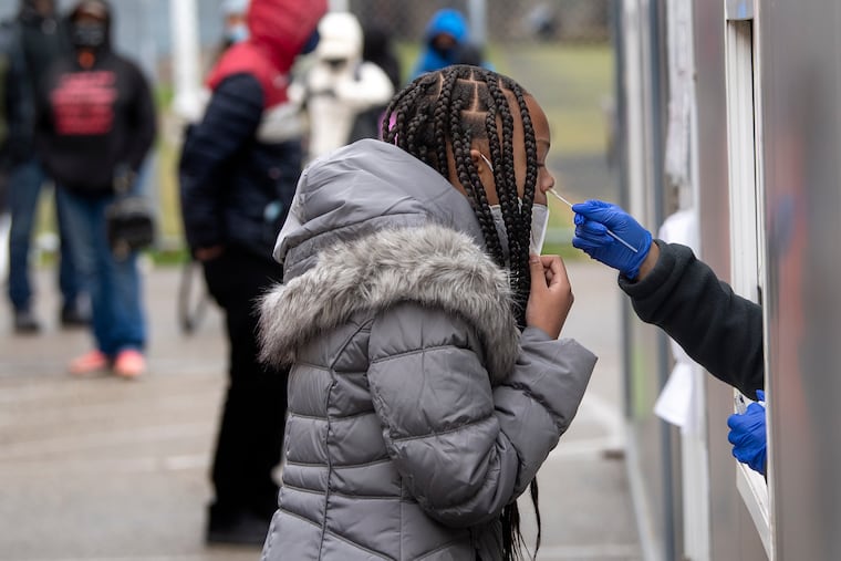 From inside a trailer, Dr. Jill Gansert administers a free COVID-19 rapid test on Wednesday morning to a woman at the Sayre Health Center testing site in West Philadelphia.