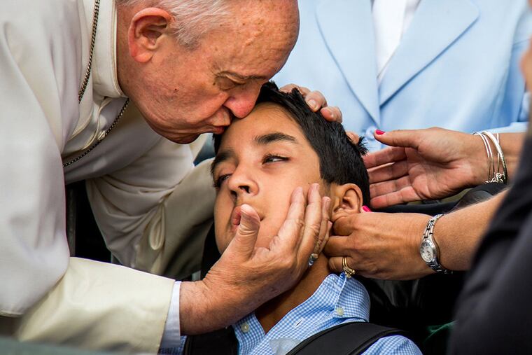 In this photo provided by World Meeting of Families, Pope Francis kisses and blesses Michael Keating, 10, of Elverson, Pa after arriving in Philadelphia and exiting his car when he saw the boy, Saturday, Sept. 26, 2015, at Philadelphia International Airport. Keating has cerebral palsy and is the son of Chuck Keating, director of the Bishop Shanahan High School band that performed at Pope Francis' airport arrival. (Joseph Gidjunis/World Meeting of Families via AP) MANDATORY CREDIT