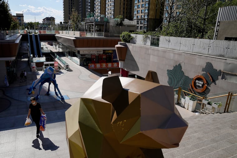 A woman carrying groceries walks by a map showing the Evergrande development projects in China, at an Evergrande city plaza in Beijing on Tuesday.
