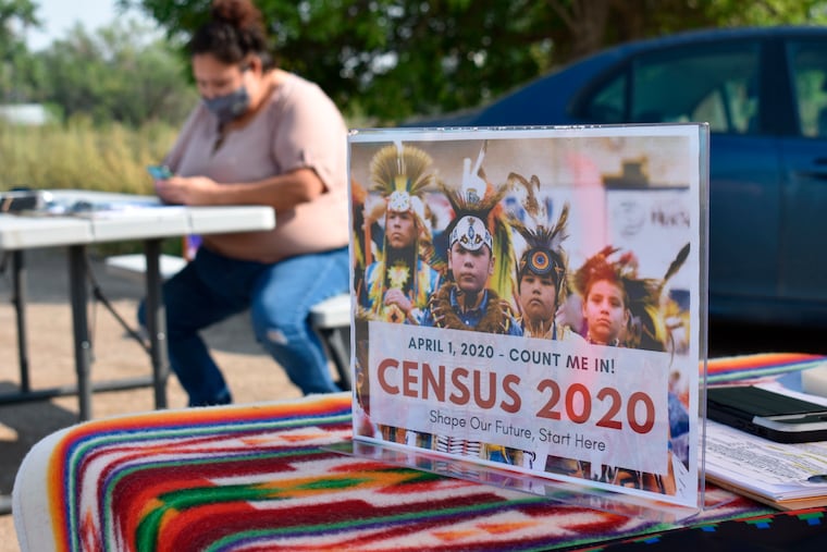 A sign promoting Native American participation in the U.S. census is displayed as Selena Rides Horse enters information into her phone on behalf of a member of the Crow Indian Tribe in Lodge Grass, Mont., Aug. 26, 2020.