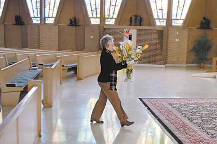 Parishioner Ann Marie Flamani carries a floral arrangement to the altar at St. Vincent Pallotti Church in Haddon Township, preparing for today’s final Mass by Msgr. Louis Marucci. “We’re very bitter,” she says. “It’s made a lot of us lose faith in the hierarchy, in the bishop.” (TOM GRALISH / Staff Photographer)