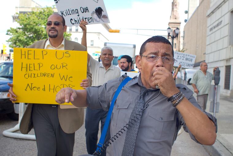 Angel Cordero, a protest organizers, chants into a microphone as he leads protesters in front of City Hall.