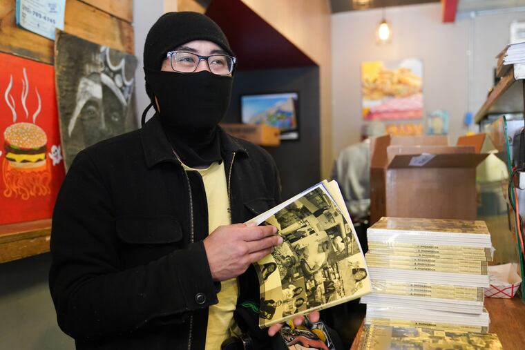 Josh Kim, who runs Spot Gourmet Burgers in Brewerytown, pages through a copy of "A Phonebook," which he's featured in and available for free with purchase at his restaurant.