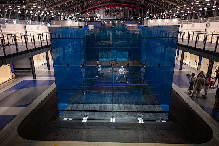 DuBois Stewart (left) and Kat Burgos, from the SquashSmarts program, play in the glass court at the center of the new Arlen Specter US Squash Center. The facility was inserted into a historic armory on 33rd Street, near the Drexel University campus.