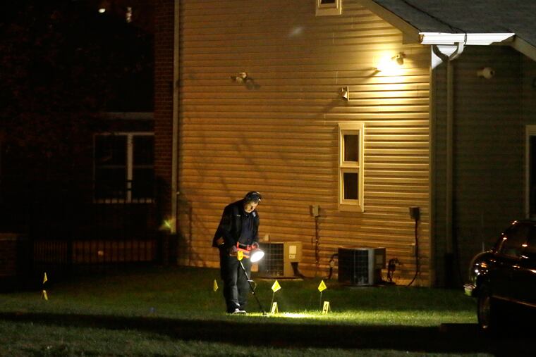 Philadelphia Police search for evidence behind homes after an off-duty policeman was shot on Friday, Nov. 18.