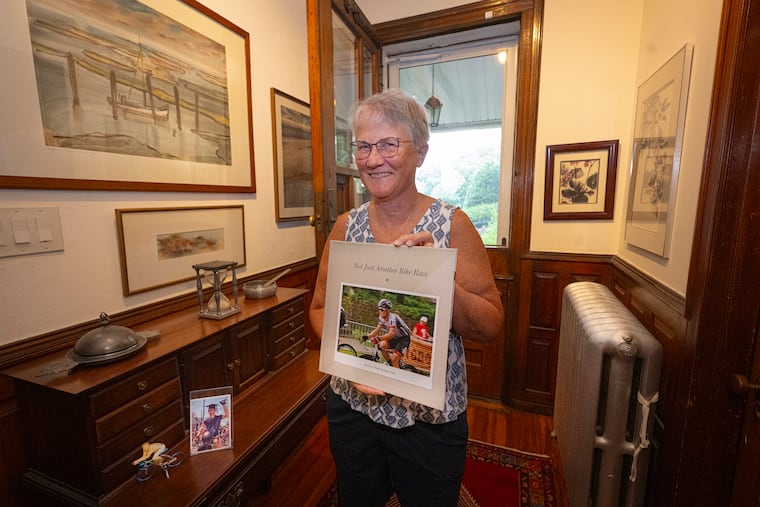 Julia Carpenter holds a book of photographs of her son, cyclist Robin Carpenter, at her home in Manayunk.