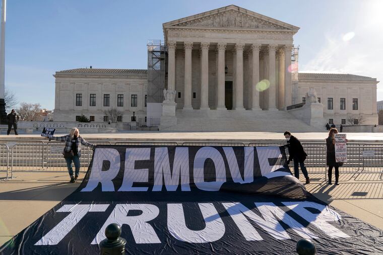 Demonstrators hold a banner outside of the Supreme Court Building. The court agreed on Wednesday to decide whether former President Donald Trump can be prosecuted on charges he interfered with the 2020 election.