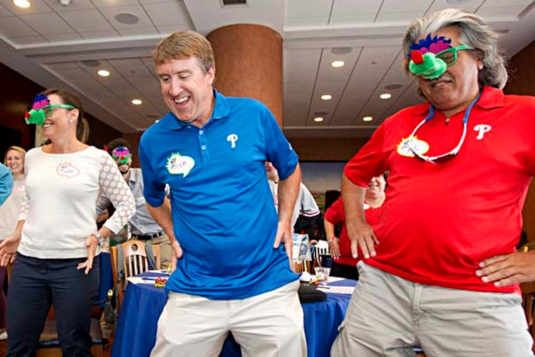 Tom Burgoyne, 3rd from left, the Phillie Phanatic leads a group in the classic Phanatic "belly whomp." L-R: Billy McHattie, Lee Ann Gehrs, Tom, Al Reisser. Tom has to think about a career Plan B. After all, the 35-pound costume, the going up and down Citizens Bank Park steps, and the "bumps and bruises" from adoring fans leaping into his arms takes a toll. Which is partly why the Phanatic, aka Tom Burgoyne, 48, of Lansdale, was leading his first full-day workshop Sept. 19, 2014, at the ballpark for business owners and professionals, making the business case for creating 'Loving Fans Loyal For Life." The workshop, organized by the New Jersey executive-retreat firm of Dillon Marcus, will be taken on the road if the demand is there, Burgoyne says. ( CHARLES FOX / Staff Photographer )