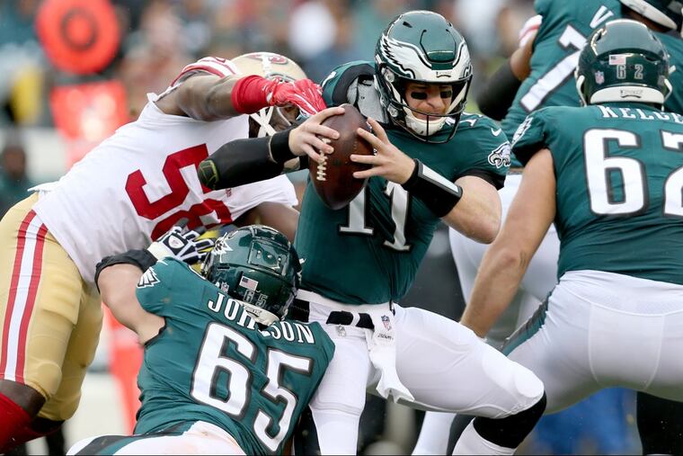 Eagles’ Carson Wentz, center, avoids 49ers’ defender Elvis Dumervil, left, during the 2nd quarter as the Philadelphia Eagles play the San Francisco 49ers in Philadelphia, PA on October 29, 2017. DAVID MAIALETTI / Staff Photographer