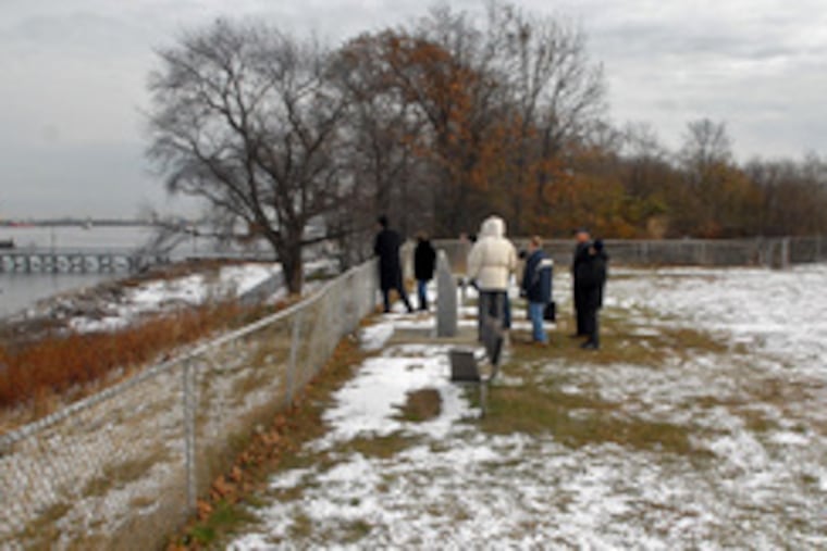 Preservationists stand near historic markers in a public park near Fort Billingsport's Delaware River site. They say they believe the fort was on higher ground, behind the oil-terminal fence.