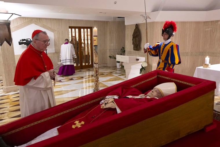 Vatican Secretary of State Cardinal Pietro Parolin, left, prays in front of the body of Pope Francis laid out in state inside his private chapel at the Vatican on Monday, April 21, 2025.
