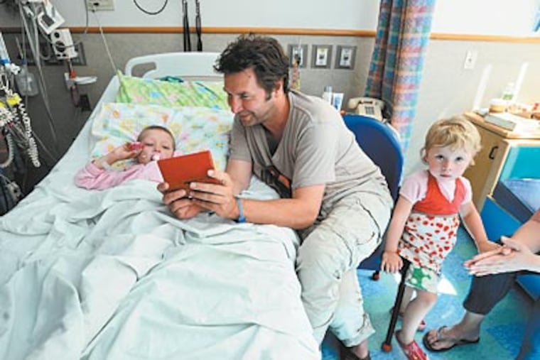 Cancer patient Lise De Boer, 5, with father Alex and sister Famke at Children’s Hospital. At the Colket building, doctors are working on new forms of treatment. (Bob Williams / For The Inquirer)
