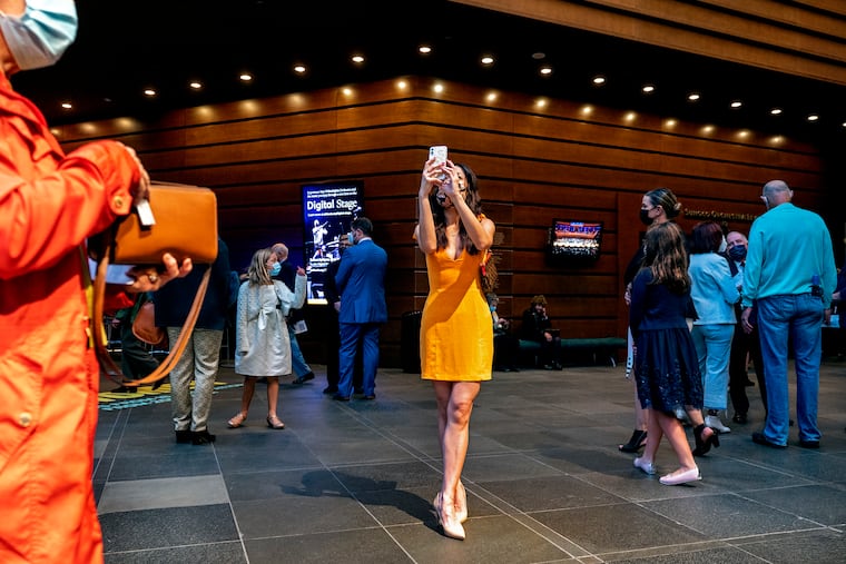 Julia Vu of Northern Liberties pauses to take a photo as.she arrives with other audience members in the lobby of the Kimmel Center Oct. 5, 2021, on opening night for the Philadelphia Orchestra at Verizon Hall.