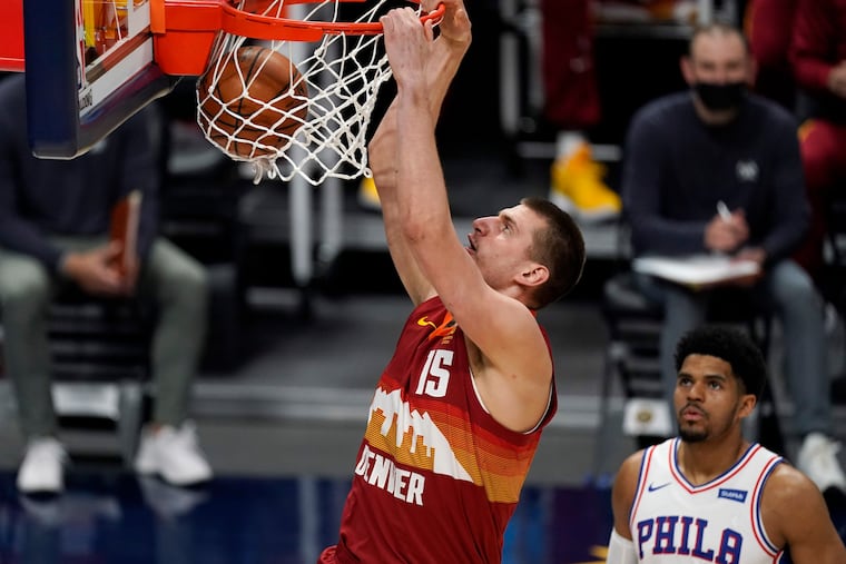 Denver Nuggets center Nikola Jokic dunks above Tobias Harris of the Sixers.