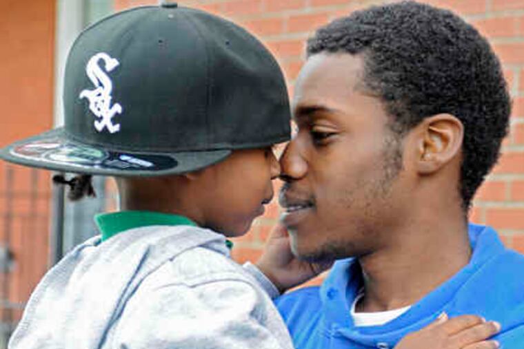 Kenny Woods, cleared in a fatal hit-and-run, holds son Za'khi, 4, outside their home on Aspen Street near 40th in West Philly.