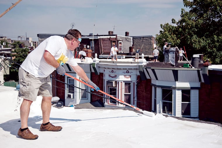 Chris Salazar works on a Seltzer Street roof with volunteers, most of whom were attending the International Roof Coatings Conference here.