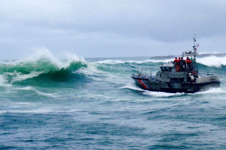 In this Tuesday, Jan. 8, 2019 photo, provided by the U.S. Coast Guard, a U.S. Coast Guard boat crew responds to three fishermen in the water after the commercial fishing vessel Mary B II capsized while crossing Yaquina Bay Bar off the coast of Newport, Ore. Authorities say three men were killed when their fishing boat capsized in rough waters off the Oregon coast. (U.S. Coast Guard via AP)