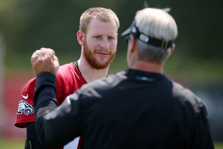 Carson Wentz (left) talking with coach Doug Pederson after training camp Friday.