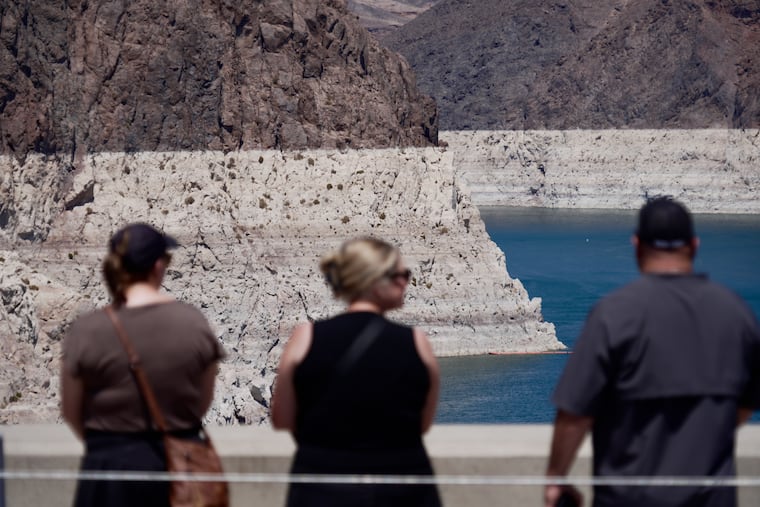 Tourists on the Hoover Dam look out at the bathtub ring of minerals that shows the former water levels of Lake Mead near Boulder City, Nev., on Friday, Aug. 7, 2026.