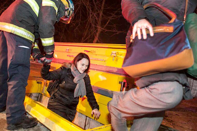Firefighters help a PATCO rider use an access hatch at Race and Seventh on Monday after an evacuation from smoke- filled cars.
