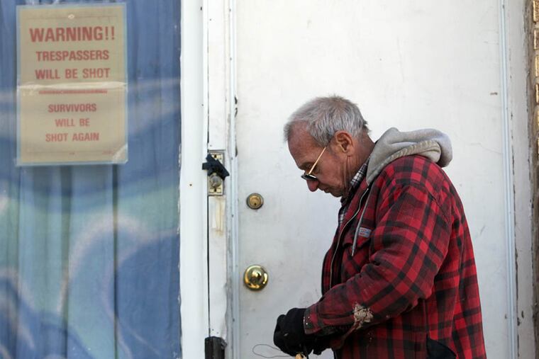 Al Schulz, who owns the apartments at 4600 Vista Street, locks the door after police clear the scene of a shooting leaving three people dead in Philadelphia, Pa. on January 11, 2015. ( DAVID MAIALETTI / Staff Photographer )