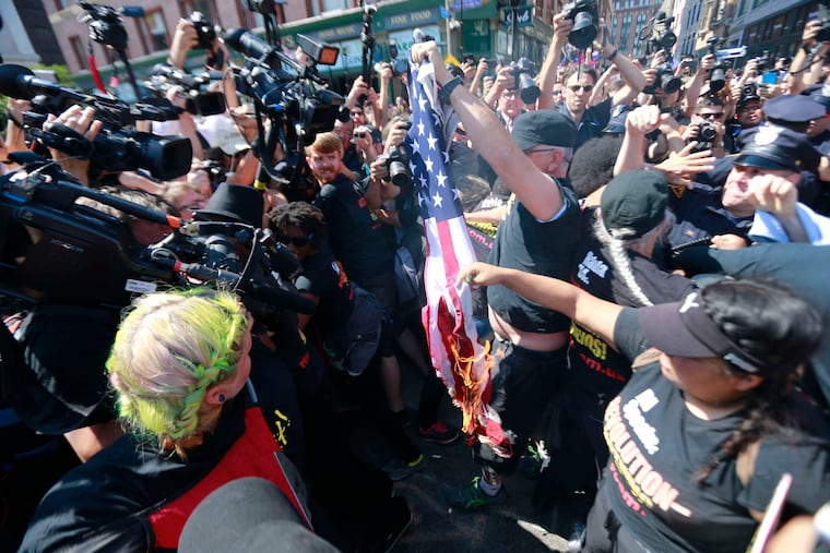 Protesters burn an American flag and scuffle with police officers near the main entrance to the convention.