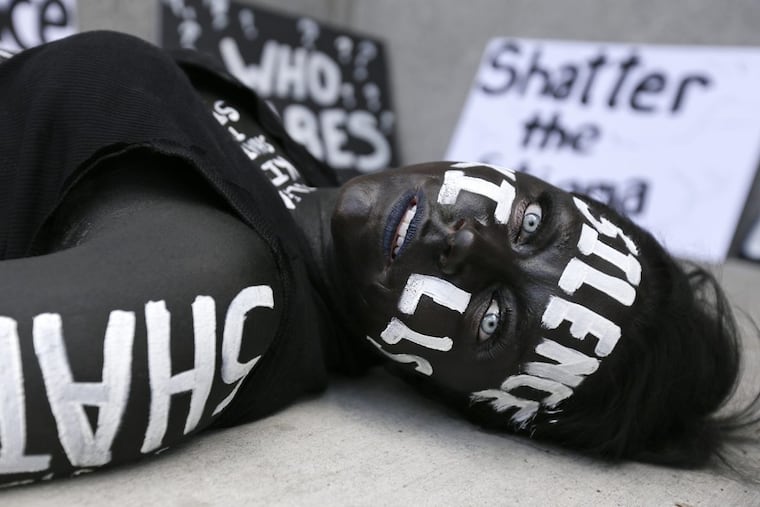 Alexis Johnson of Harrisburg, Pa. lays motionless at City Hall in Phila., Pa. on July 16, 2017. Johnson, a former heroin addict, was painted black with messages like "silence kills" and "shatter the stigma" painted on her body with the purpose of bringing attention to the heroin epidemic. ( ELIZABETH ROBERTSON / Staff Photographer )