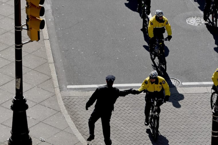 A Philadelphia Police officer greets a fellow bicycle officer as they head up South Broad street ahead of the Eagles Super Bowl victory parade February 8, 2018. TOM GRALISH / Staff Photographer