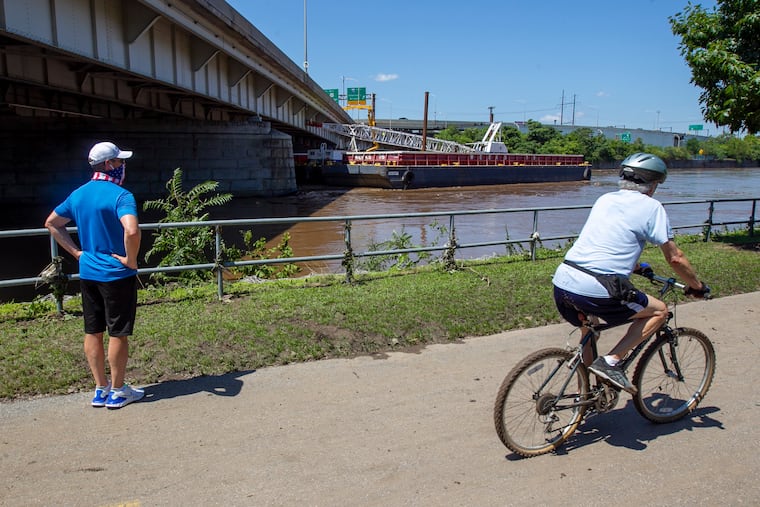 Two men take a look at the barge that struck the side of the Vine Street Expressway as a result of heavy rains from the remnants of Tropical Storm Isaias last August.