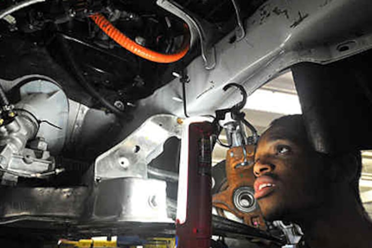 Senior Sekou Kamara checks the Ford hybrid, one of two cars the West Philadelphia team is working on. (Sharon Gekoski-Kimmel / Staff)