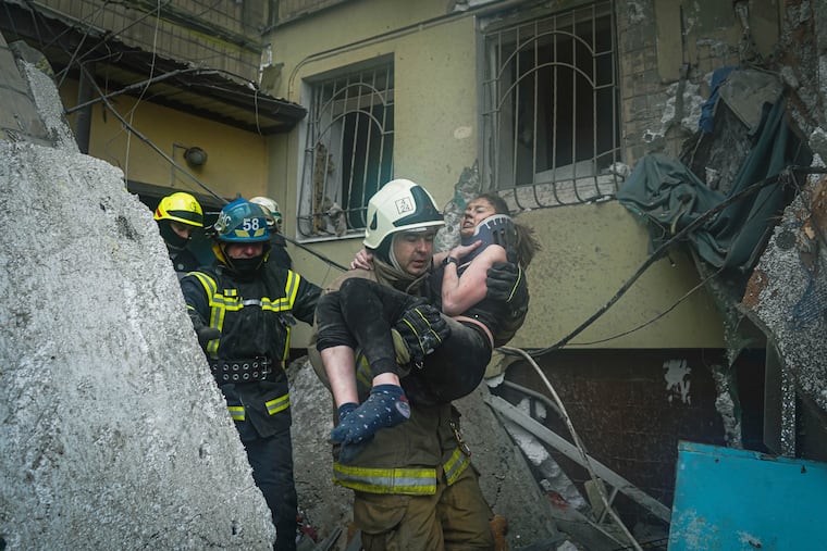 A Ukrainian State Emergency Service firefighter carries a wounded woman out of the rubble from a building after a Russian rocket attack on Saturday in Dnipro, Ukraine, Sunday, Jan. 15, 2023.