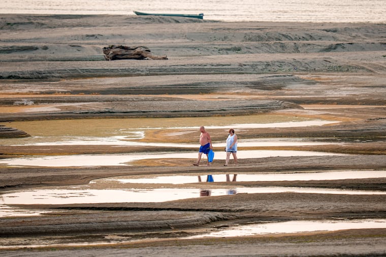 People walk on a sandbank on the Danube River as usually submerged areas are exposed amid exceptionally low water levels, in Rasova, Romania, Friday, Aug. 7, 2026. Europe has experienced a series of heat waves and droughts this summer.