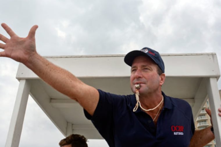 Bob "Domino" Spano waves and blows his whistle to get swimmers back between the flags, on the beach in Ocean City Sept. 3, 2012. He is retiring after 30 years on the Ocean City Beach Patrol. (TOM GRALISH / Staff Photographer)