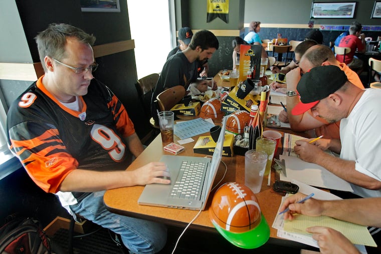 Brian Sherman, left, using his laptop to record moves in his team's fantasy football draft, at a Buffalo Wild Wings restaurant in Cincinnati.