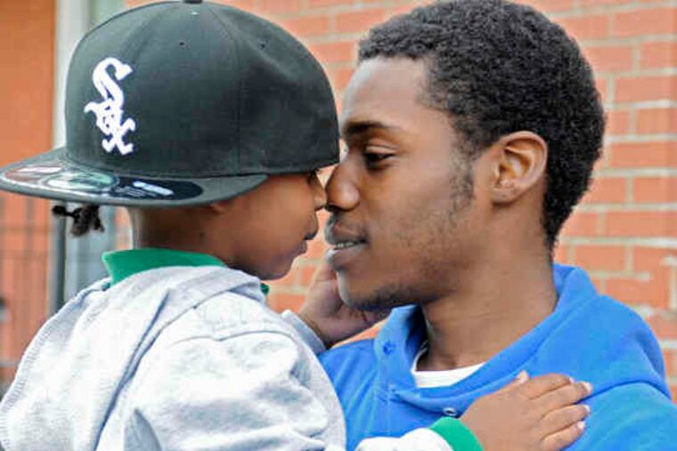Kenneth Woods holds his son Za'khi, 4, outside his West Phila. home after his release. When he learned about the fatal crash for which he was charged, he said, "I was just lost."