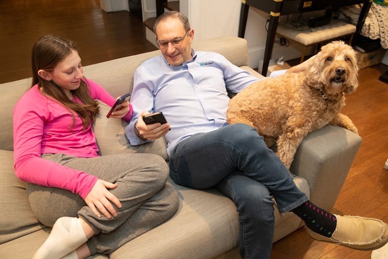 Will Fulmer, who owns an IT company, said he has had issues with cell service in and around his Bala Cynwyd home. He got so frustrated a year ago that he drove around and mapped the cell and data coverage in the region, showing dead spots. Will and his daughter, Shira, with their dog, Max, are shown using their phones on Jan. 24, 2024.