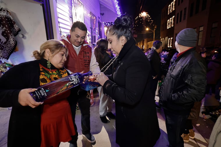 Reyna Guadalupe Navarro (left) pours tequila for guests during a posada at her home in South Philadelphia on Dec. 17, 2021.