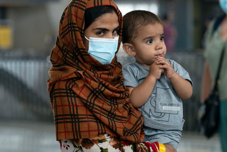 Families evacuated from Kabul, Afghanistan, walk through the terminal before boarding a bus after they arrived at Washington Dulles International Airport, in Chantilly, Va., on Monday, Aug. 23, 2021.