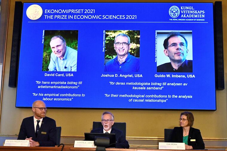 Permanent Secretary of the Royal Swedish Academy of Sciences Goran K Hansson, center, announces the 2021 Nobel prize for economics, flanked by members of the Royal Swedish Academy of Sciences Peter Fredriksson, left, and Eva Mork, during a press conference at the Royal Swedish Academy of Sciences, in Stockholm, Sweden, Monday, Oct. 11, 2021. From left on the screen above are the winners David Card of the University of California at Berkeley; Joshua Angrist from the Massachusetts Institute of Technology; and Guido Imbens from Stanford University.