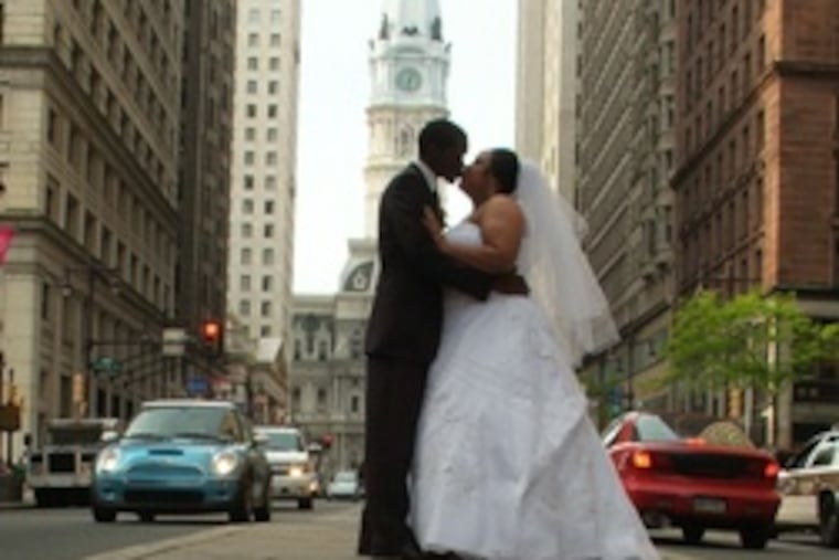 The couple kiss in Center City as William Penn watches from atop City Hall.