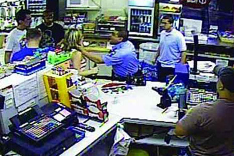 This still from a surveillance video at a Northeast Philadelphia convenience store shows Officer Alberto Lopez grabbing a woman by the neck while the clerk and three of the woman’s friends look on.