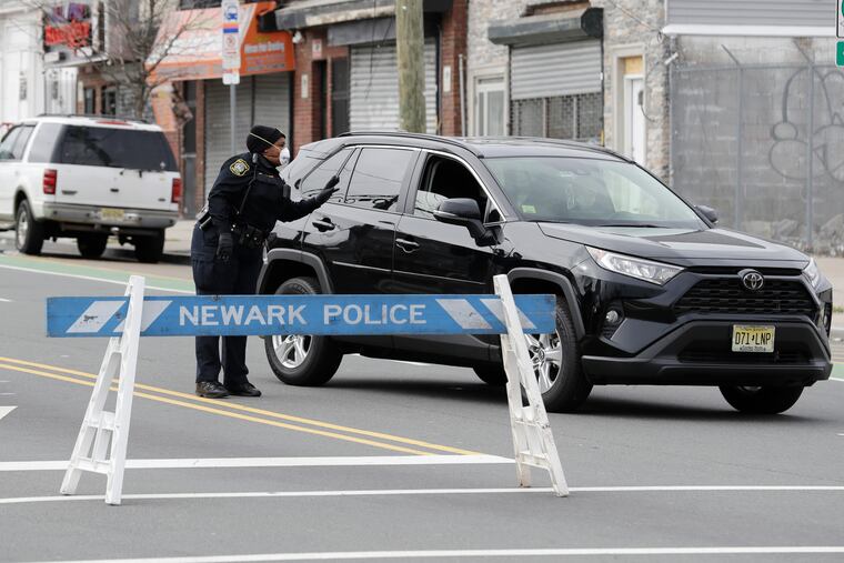 A police officer talks to a motorist at an intersection on the border between Irvington and Newark, N.J. The police officers were reminding pedestrians and the occasional motorist to avoid unnecessary travel and practice social distancing.